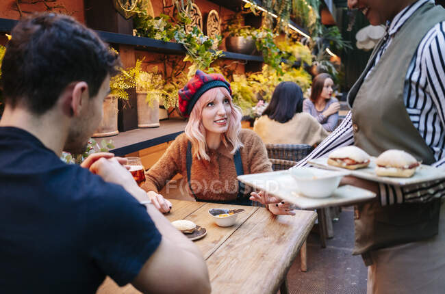 Cameriera sta servendo cibo per coppie, seduto nel ristorante — Foto stock