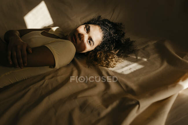 Retrato de una joven atractiva tumbada en la cama a la luz del sol — ropa  interior, Veinte años - Stock Photo | #472806208