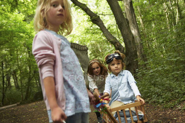 Children with hand cart playing in forest — Stock Photo