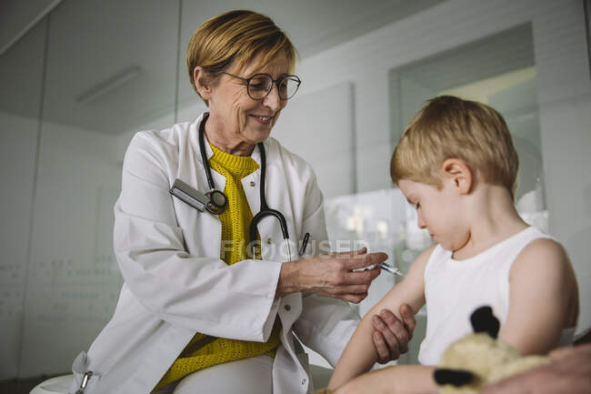Pediatra che inietta il vaccino nel braccio del bambino — Foto stock