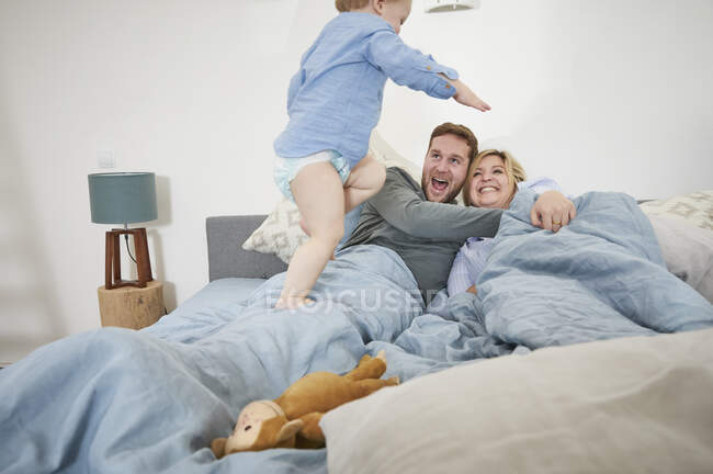 Familia relajándose y saltando en la cama - foto de stock
