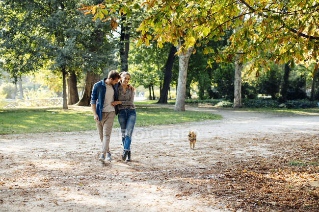 Happy young couple with dog in a park — Stock Photo