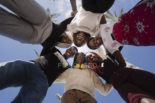 Portrait d'adolescentes heureuses et de jeunes hommes se blottissant sous le ciel bleu — Photo de stock