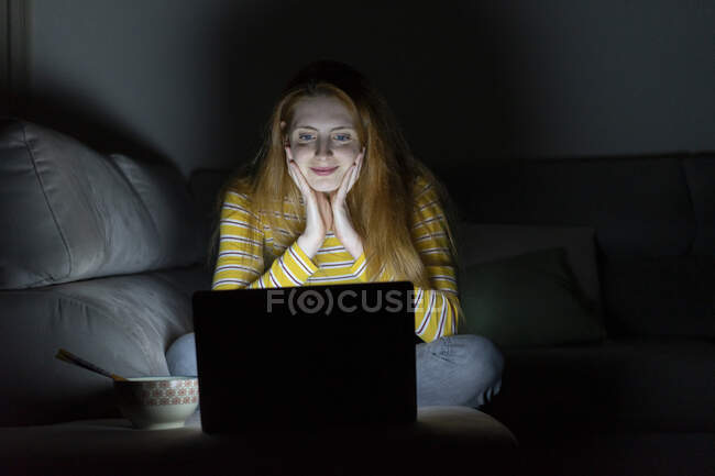 Mujer joven que tiene una videoconferencia portátil en el sofá en casa - foto de stock