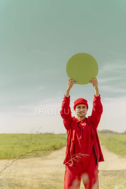 Portrait de jeune homme vêtu de rouge tenant le cercle vert — Photo de stock
