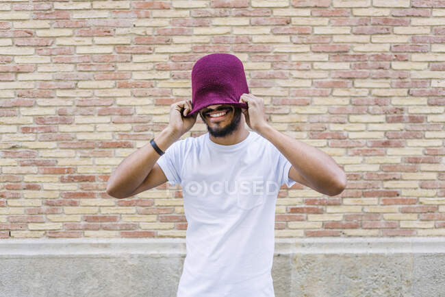 Ritratto di giovane uomo ridente che copre gli occhi con il suo cappello di lana — Foto stock