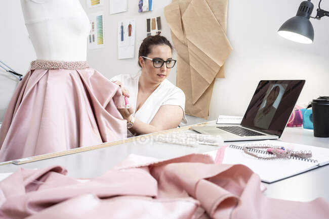 Couturière travaillant dans un atelier de tailleur et présentant une jupe par appel vidéo — Photo de stock