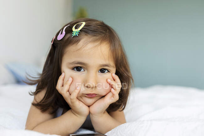 Portrait of bored little girl lying on bed — Stock Photo