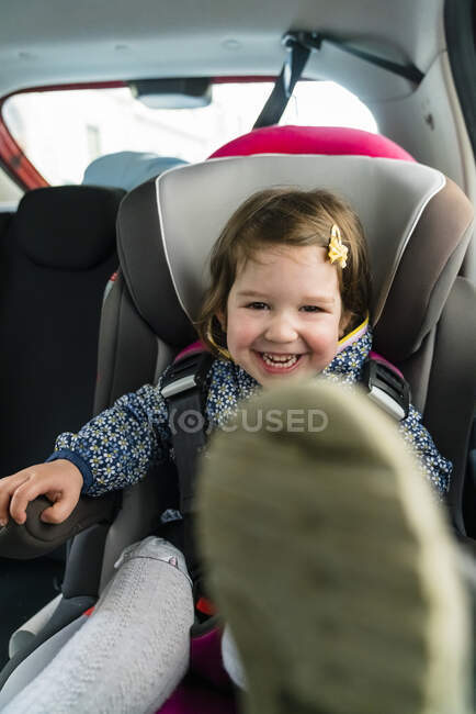 Portrait de la petite fille riante assise sur le siège de l'enfant en voiture — Photo de stock
