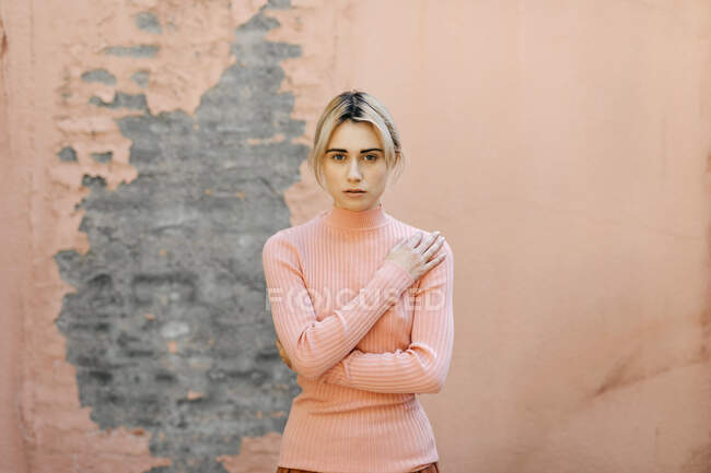 Portrait de femme blonde portant un pull col roulé rose devant un mur rose — Photo de stock