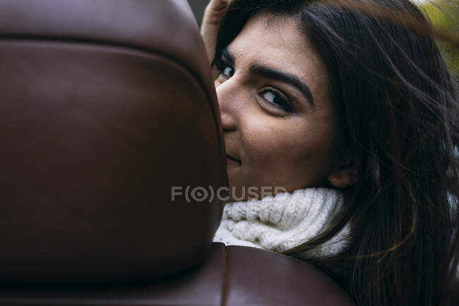 Retrato de mujer joven mirando a través de asientos mientras disfruta en el coche - foto de stock