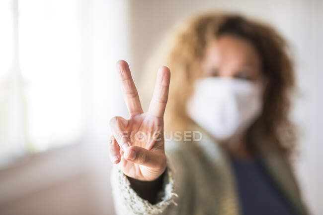 Женщина в маске делает знак победы — стоковое фото