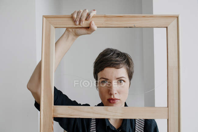 Retrato de una pintora que sostiene un marco en su estudio - foto de stock