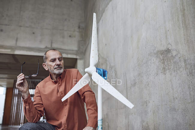 Ingegnere senior che lavora su soluzioni di energia eolica, guardando turbina eolica — Foto stock