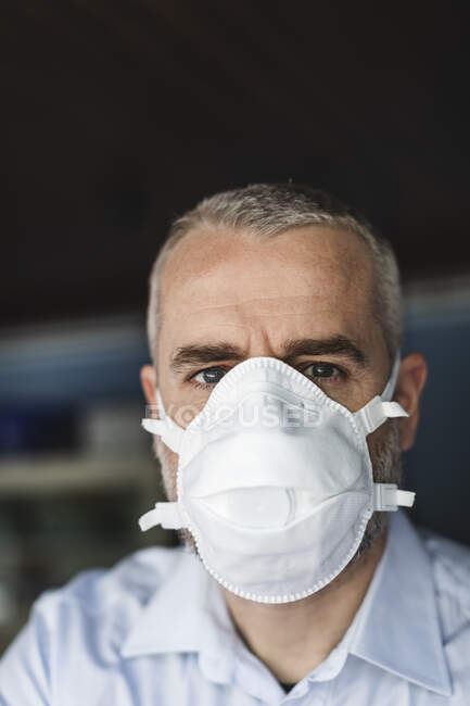 Reifer Mann mit Schutzmaske blickt in Kamera — Stockfoto