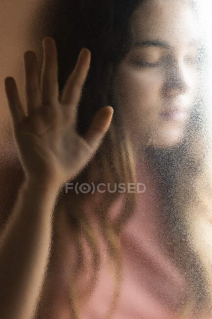 Retrato de adolescente con los ojos cerrados detrás del cristal - foto de stock