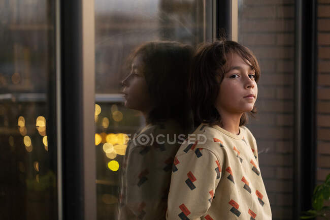 Boy leaning on window, mirrored in glass pane — Stock Photo