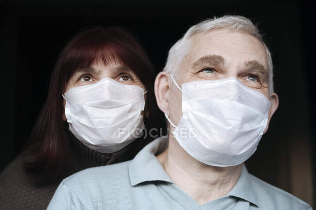 Retrato de casal sênior usando máscaras em casa — Fotografia de Stock