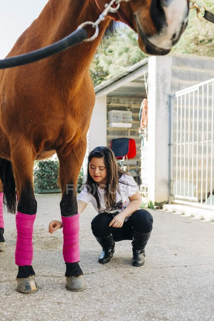 Adolescente com síndrome de down cuidando do cavalo e preparando o cavalo para montar — Fotografia de Stock