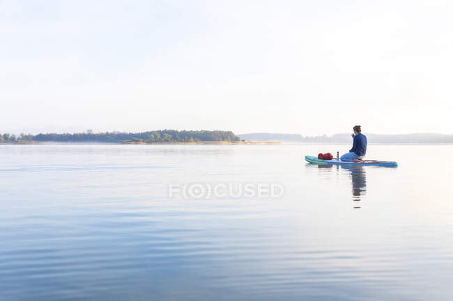 Woman sitting on sup board in the morning on a lake, Germany — Stock Photo