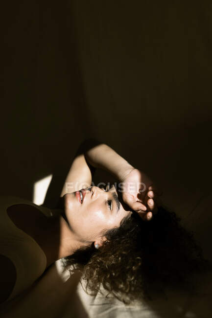 Retrato de una joven atractiva tumbada en la cama a la luz del sol - foto de stock