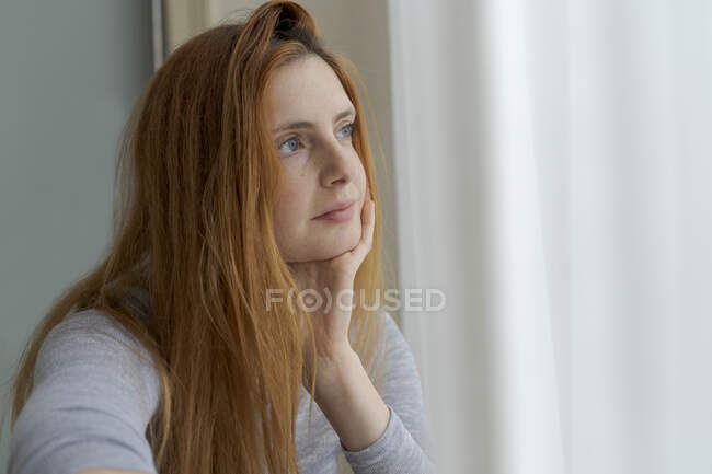 Портрет серйозної молодої жінки, що дивиться у вікно. — стокове фото