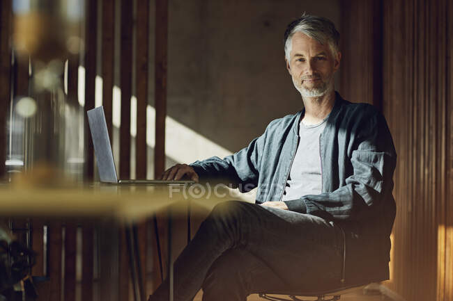 Casual businessman sitting in his sustainable office, looking at camera — Stock Photo