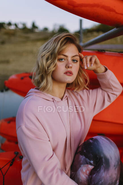 Retrato de jovem loira usando camisola com capuz rosa no molhe — Fotografia de Stock