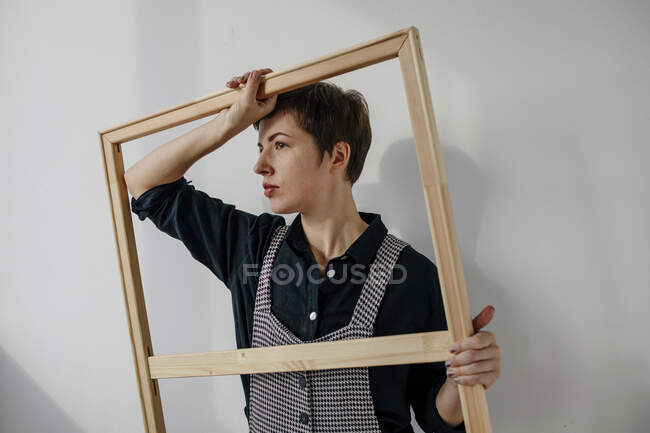 Portrait of a female painter holding a picture frame in her studio — Stock Photo
