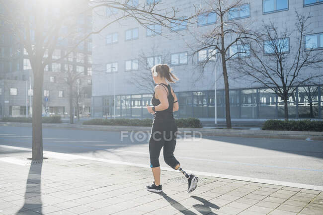 Jovem esportiva com prótese de perna correndo na cidade — Fotografia de Stock