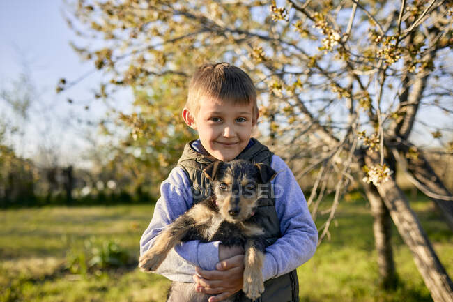 Portrait de garçon tenant un chien sur une prairie — Photo de stock