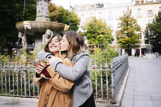 Дві щасливі молоді жінки обіймаються в місті — стокове фото