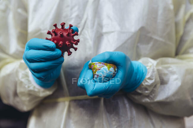 Trabajador de la salud sosteniendo el modelo de Corona Virus, aplastando un mini globo - foto de stock