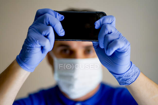 Доктор з маскою обличчя, за допомогою смартфона. — стокове фото