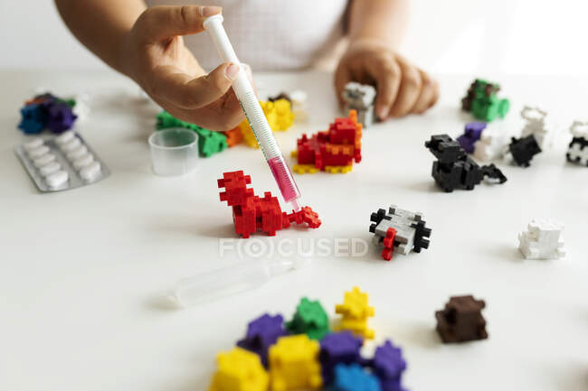 Vista de los cultivos de un niño jugando con bloques de construcción y jeringa durante la cuarentena - foto de stock