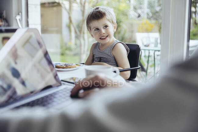Menino assistindo pai trabalhando em casa — Fotografia de Stock