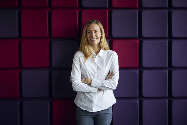 Ritratto di donna sorridente a un muro viola — Foto stock