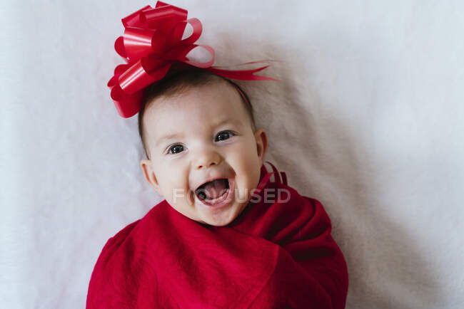 Ritratto di bambina felice con nastro rosso sulla testa avvolto in una coperta rossa — Foto stock