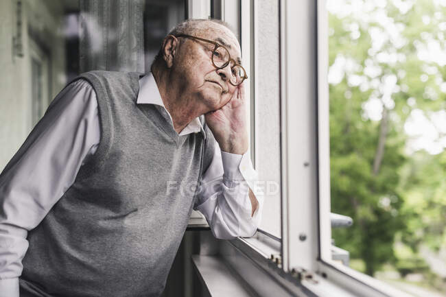 Ritratto di uomo anziano triste che guarda fuori dalla finestra — Foto stock