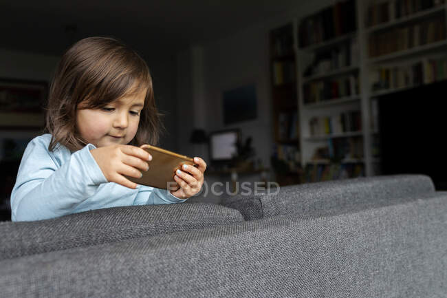 Porträt eines Kleinkindes, das sein Smartphone zu Hause benutzt — Stockfoto