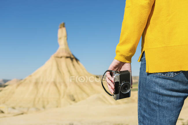 Woman holding a vintage camera in desertic landscape of Bardenas Reales, Arguedas, Navarra, Spain — Stock Photo