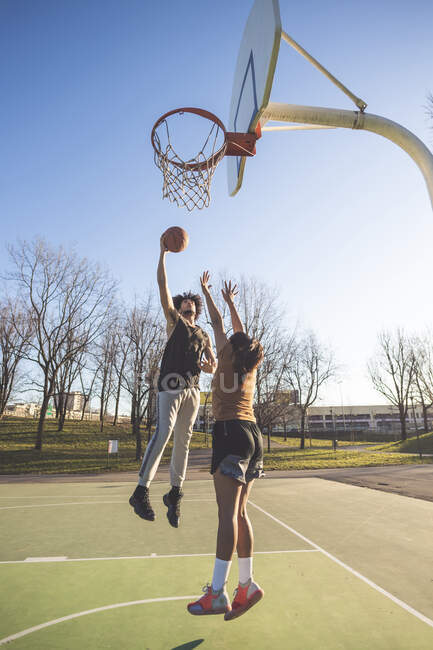 Jovem e mulher jogando basquete na quadra — Duas pessoas