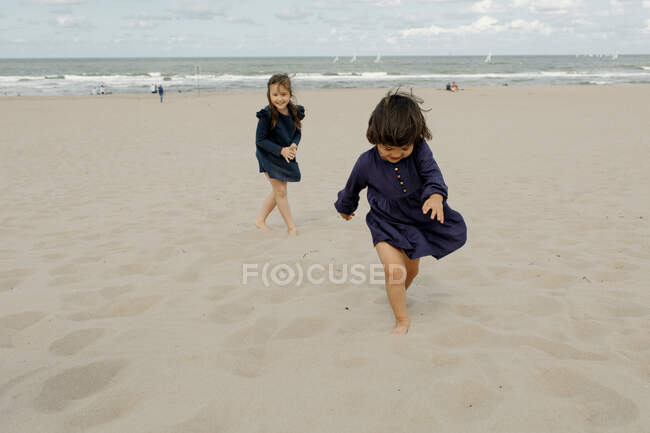 Две маленькие девочки, играющие на пляже, Шевенхем, Нидерланды — стоковое фото