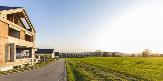 Germania, Baden-Wurttemberg, Waiblingen, Campo e strada di campagna di fronte alla casa moderna in costruzione — Foto stock