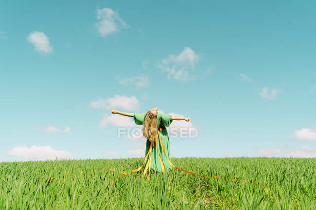 Молода жінка в зеленій сукні, що вигинається назад у полі — стокове фото