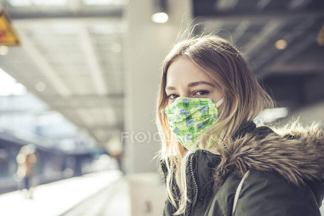 Retrato de jovem mulher usando máscara na plataforma da estação — Fotografia de Stock