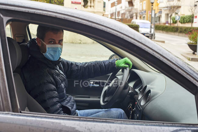 Porträt eines maskierten Mannes, der in der Stadt Auto fährt — Stockfoto