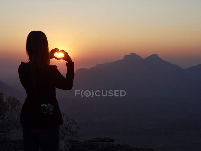 Silhouette of woman shaping heart with her hands at sunset, Serra da Leba, Angola — Stock Photo