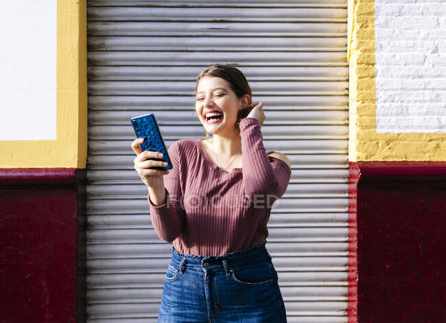 Happy woman using smartphone at a building in the city — Stock Photo
