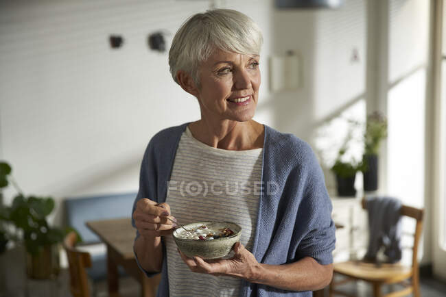 Portrait of senior woman holding bowl of granola with yoghurt and berries — Stock Photo
